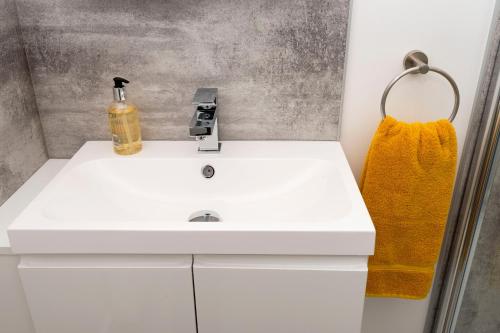 因弗内斯No. 6 Apartment的浴室设有白色水槽和黄色毛巾。