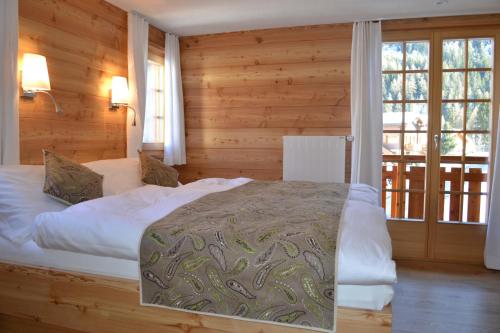 格里门茨Hôtel Mélèze B & B的卧室配有一张床铺,位于带木墙的房间内