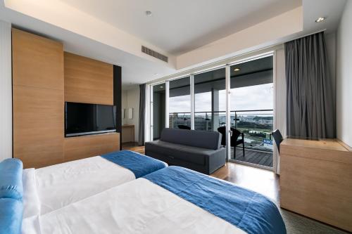 那霸那霸东急REI酒店的一间卧室配有一张床、一台电视和一张沙发