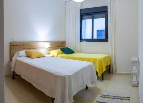 托雷德尔马尔Apartamento Atalaya Playa的一间卧室设有两张带黄床单的床和窗户。