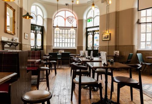 伦敦维多利亚白渡轮酒吧爱情旅舍的餐厅设有桌椅和窗户。