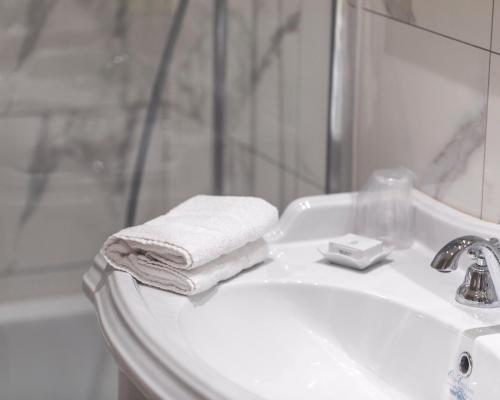 里尔格兰德贝尔维尤 - 大广场酒店的白色浴室水槽、毛巾和淋浴