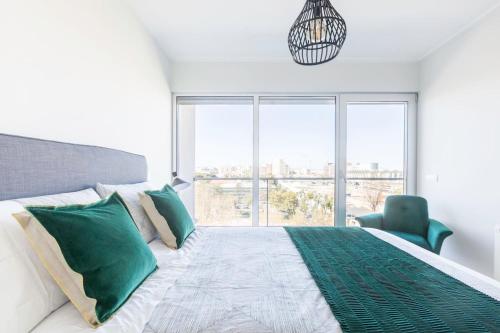 里斯本Amazing Flat - Pool and Parking的一间卧室配有一张带绿色枕头的床和一扇窗户