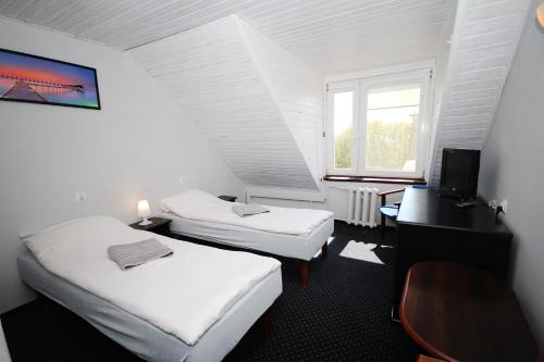 库瑞尼卡慕斯卡Pensjonat Resident的客房设有两张床、一张桌子和一个窗户。
