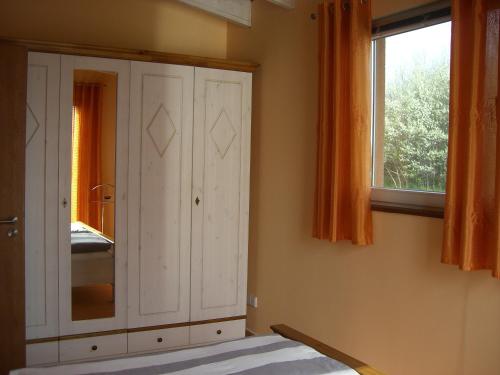 Usedom Town哈弗边纱架庭院公寓的卧室配有白色橱柜和窗户。