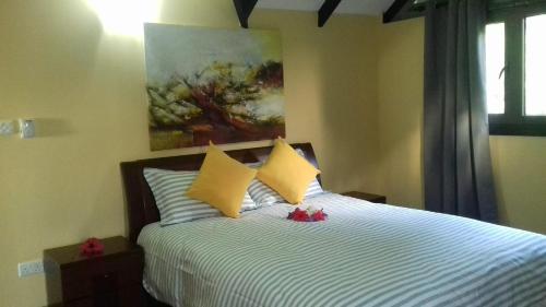 维多利亚SHAY LYAH SELF CATERING的一间卧室配有一张带黄色枕头的床和一幅画