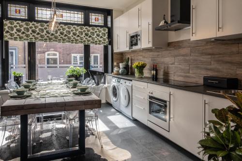 艾曾代克Het Zeeuwse Bloemenhuis的厨房配有白色橱柜和1张带洗衣机的桌子。
