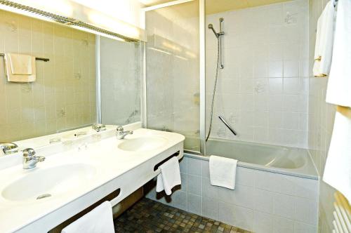 图特林根Hotel Café Schlack的浴室配有2个盥洗盆、淋浴和浴缸。