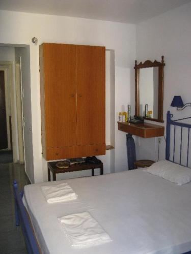 罗德镇EL GRECO的一间卧室配有一张床和一个木制橱柜