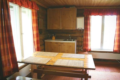 LemmenjokiPaltto Elämysretket的厨房配有木桌和2扇窗户。