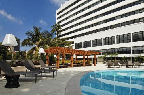 萨尔瓦多巴伊亚威什酒店的一座带游泳池和椅子的酒店和一座建筑