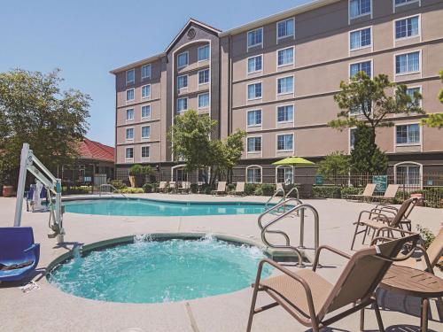 俄克拉何马城俄克拉荷马城西北高速公路拉金塔旅馆及套房酒店的一座带椅子的酒店游泳池以及一座建筑