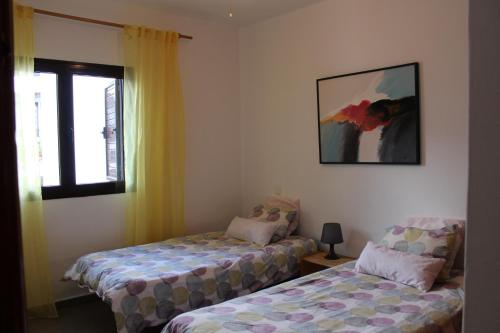 蒂亚斯Apartamento Steffi的客房设有两张床和一扇带照片的窗户。