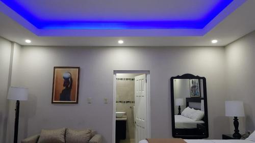 金斯敦克里斯塔尔别墅酒店的蓝色天花板、一张床和镜子的客房