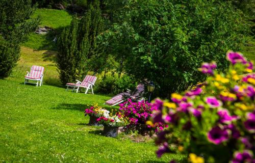 萨斯阿尔马格尔Hotel Alpenhof的花园里的两把椅子,花草丛生