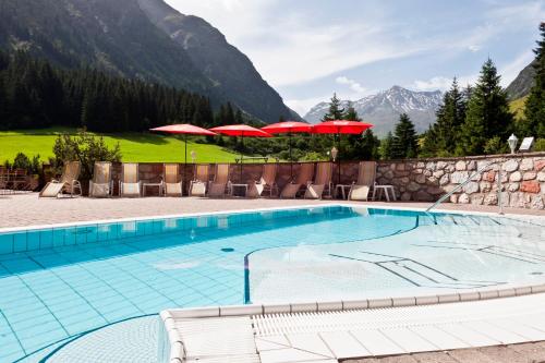 皮茨河谷圣莱昂哈德斯波特赛普尔维塔尔酒店的一个带红伞和山的游泳池
