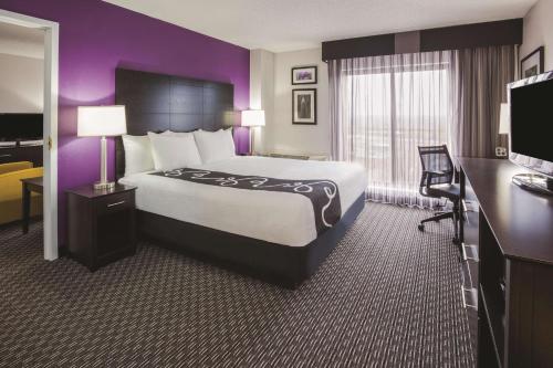 布卢明顿明尼阿波利斯布卢明顿西区拉昆塔套房酒店的酒店客房设有一张大床和紫色的墙壁。