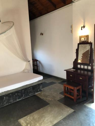 尼甘布阿拉利亚别墅酒店的一间卧室配有一张床和一张桌子上的电视