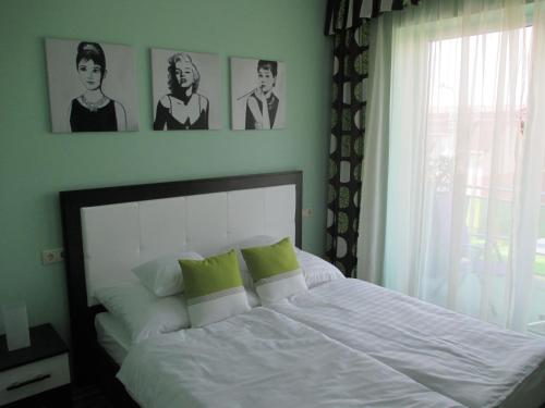 萨尔瓦尔萨尔瓦尔阿尔法公寓的卧室配有一张白色床,墙上挂有两张照片