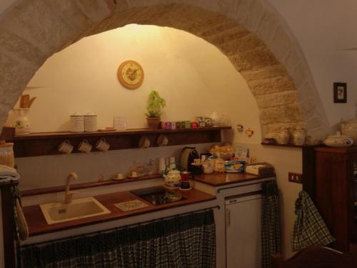 阿尔贝罗贝洛Miratrulli Apartment & Trullo dell'Aia的厨房设有水槽和带拱门的台面