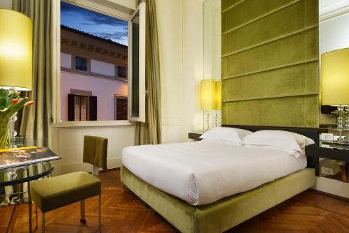 佛罗伦萨Brunelleschi Hotel的一间卧室配有一张床、一张书桌和一个窗户。
