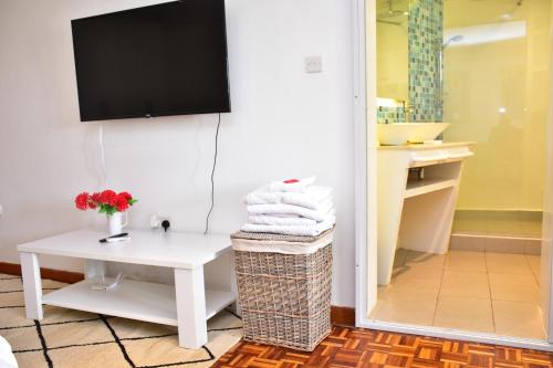 内罗毕Maison Mitwaba的浴室配有白色桌子和墙上的电视。