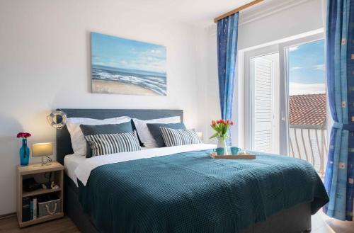 沃迪切华伦天奴公寓酒店的一间卧室配有一张带蓝色毯子的床和窗户。