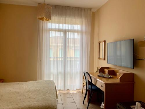 阿尔巴·阿德里亚蒂卡Hotel La Pergola的一间卧室配有一张桌子、一台电视和一张床