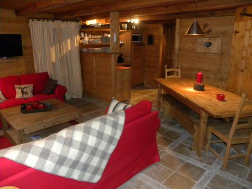 蒂涅CHALET GRINCH 90m2, 3 Sdb, skis aux pieds, wifi的客厅配有红色的沙发和木桌