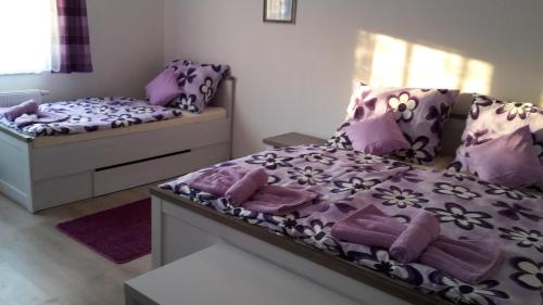 米库洛夫Ubytování LILA的一间卧室配有两张紫色和白色床单