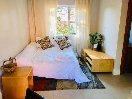 约翰内斯堡Kilkenny Cottages 2 bedroom unit的卧室配有带枕头的床铺和窗户。