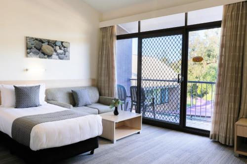 诺拉Parkhaven的一间卧室配有一张床和一张沙发,并设有一个阳台