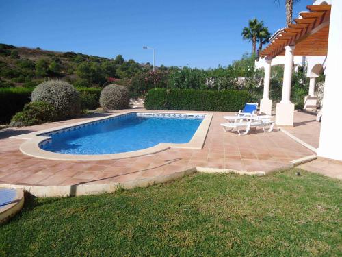 布德恩斯Lovely Burgau villa just 3 mins walk from beach的一个带两把椅子的游泳池和一个庭院