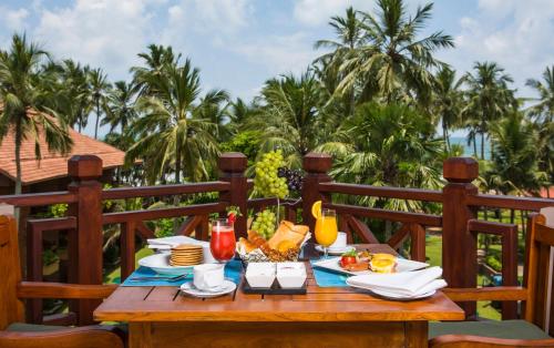 卡卢特勒皇家棕榈海滩酒店的一张木桌,上面有食物,背后有棕榈树