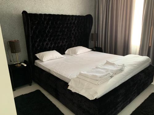 北马马亚-讷沃达里Raph的一张带黑色床头板、白色床单和枕头的床