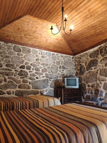 CovideCasa Padre Alexandre的一间卧室设有两张床和石墙