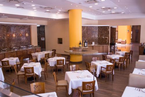 克雷塔罗米拉贝尔酒店 的一间设有白色桌椅的餐厅和一间酒吧