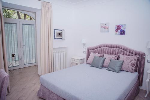 拉维罗La Gemma di Ravello的一间卧室配有一张大床,配有粉色和蓝色的枕头