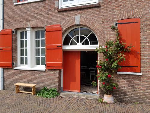 斯希丹Het Pakhuis Schiedam的通往砖砌建筑的大门,有红色的门