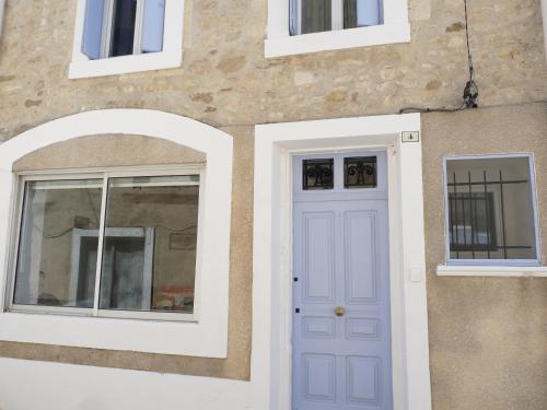 佩里阿克海appartement de la callade的一座带蓝色门和两扇窗户的房子