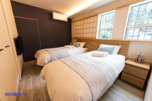 箱根Guest Villa Hakone Yumoto RiverSide的带2扇窗户的小客房内的2张床