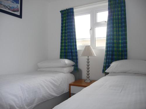 佩伦波斯151 Perran Sands的客房设有两张床和一个带窗帘的窗户。