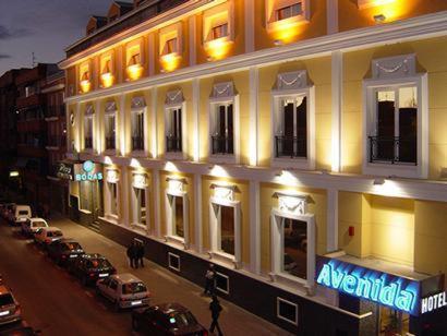 莱加内斯莱加内斯阿文尼达酒店的一座大型建筑,前面有汽车停放