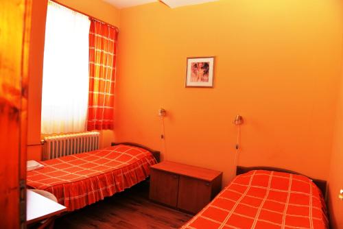 莫伊科瓦茨Hotel Dulovic的橙色墙壁客房的两张床