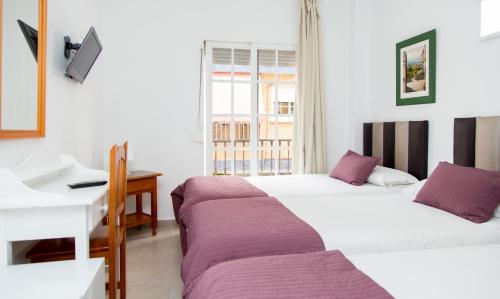 福恩吉罗拉Hotel Marbella的配有书桌和书桌的客房内的两张床