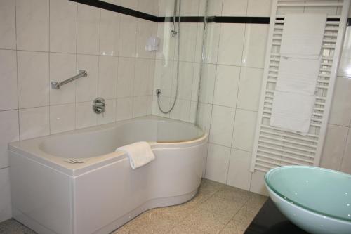 威森斯海德Hotel Retterath am Nürburgring的浴室配有白色浴缸及水槽