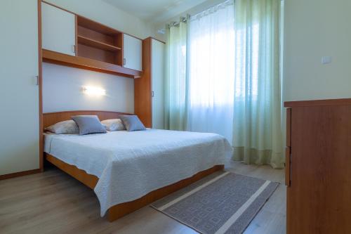 拉布Apartments & Rooms Sanja的一间卧室设有一张床和一个大窗户