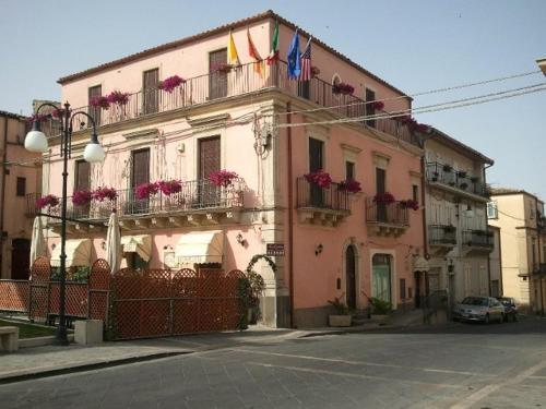 GrammicheleIl Rustico的一座粉红色的建筑,阳台上挂着旗帜和鲜花