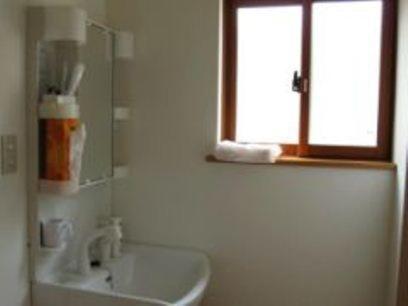 山形市敏太郎小木屋旅馆的白色的浴室设有水槽和窗户。
