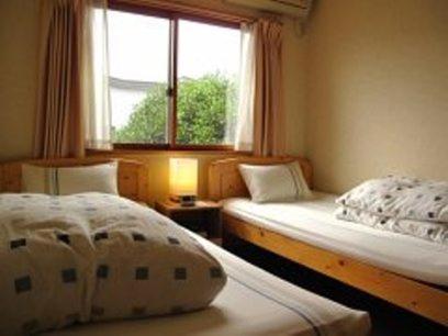 山形市敏太郎小木屋旅馆的一间卧室设有两张床和窗户。